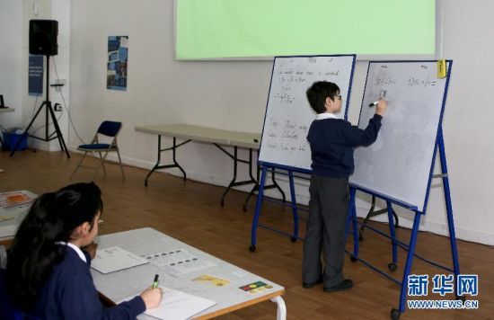 一名三年级(相当于国内二年级)的小学生在白板上用竖式计算 一名三年级(相当于国内二年级)的小学生在白板上用竖式计算